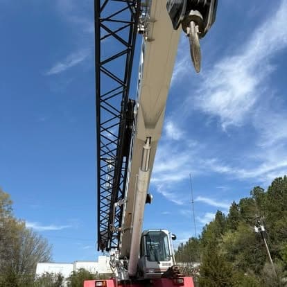 The extended boom and hook block of a rough terrain crane against a clear blue sky.
