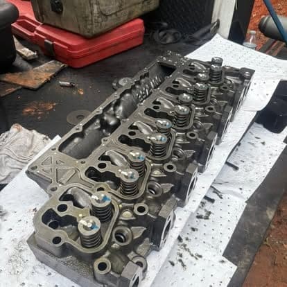 A cleaned and reassembled diesel cylinder head on the bench, valve springs and rocker pedestals installed.